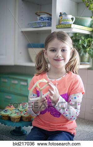 Stock Photograph - Caucasian girl licking mixing paddle in kitchen. Fotosearch