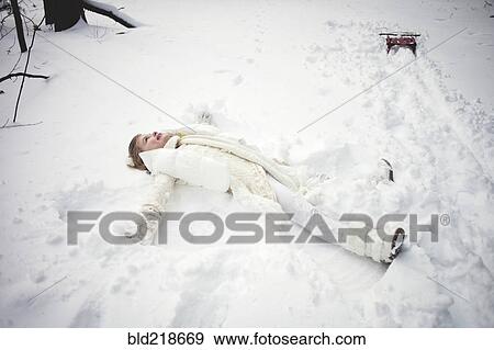 Stock Photo - Caucasian girl making snow angel in field. Fotosearch