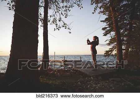 Caucasian girl photographing sunset and lake View Large Photo Image Stock Image - Caucasian girl photographing sunset and lake. Fotosearch