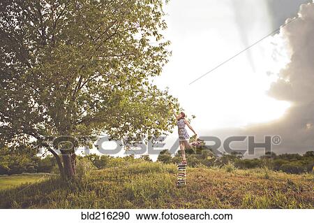 Stock Image - Caucasian girl picking fruit in orchard. Fotosearch