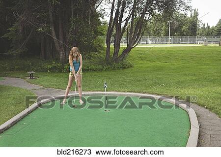 Stock Image - Caucasian girl playing miniature golf. Fotosearch