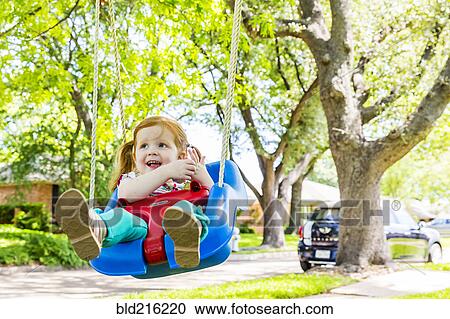 Caucasian girl playing on swing in front yard View Large Photo Image Stock Image - Caucasian girl playing on swing in front yard. Fotosearch
