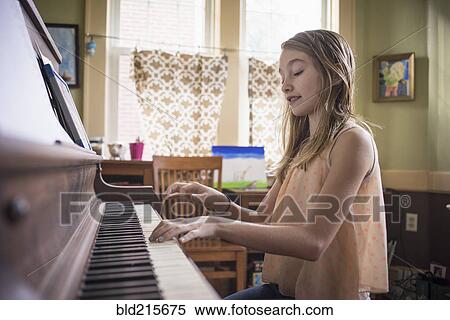 Stock Photography - Caucasian girl playing piano in living room. Fotosearch