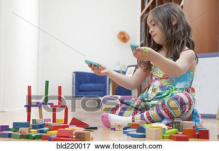 Stock Photo - Caucasian girl playing with blocks on living room floor. Fotosearch