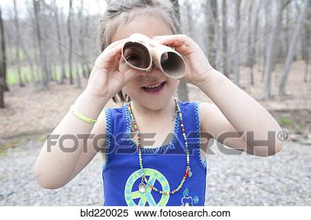 Stock Photography - Caucasian girl playing with cardboard tubes in forest. Fotosearch