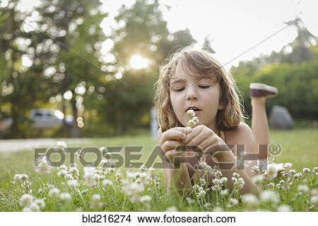 Picture - Caucasian girl playing with flowers in backyard. Fotosearch