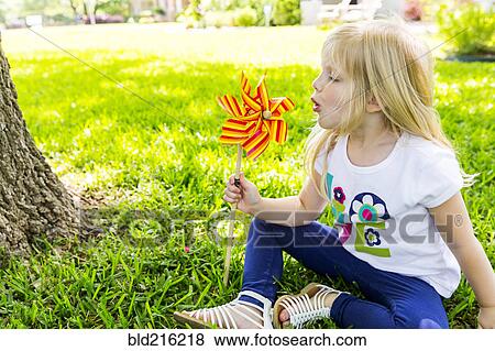 Stock Photo - Caucasian girl playing with pinwheel in backyard. Fotosearch