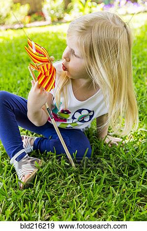Caucasian girl playing with pinwheel in backyard View Large Photo Image Stock Photo - Caucasian girl playing with pinwheel in backyard. Fotosearch