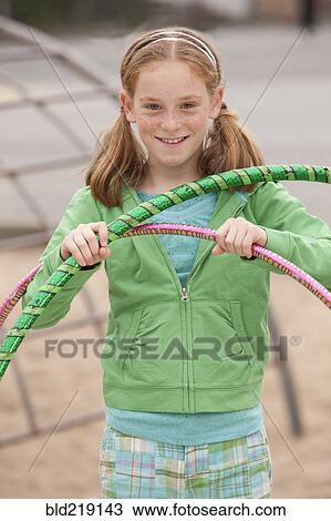 Stock Image - Caucasian girl playing with plastic hoops at playground. Fotosearch