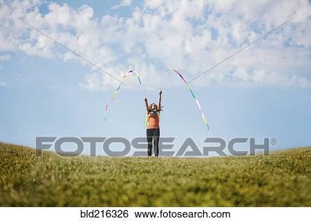 Stock Photograph - Caucasian girl playing with ribbons on hilltop. Fotosearch
