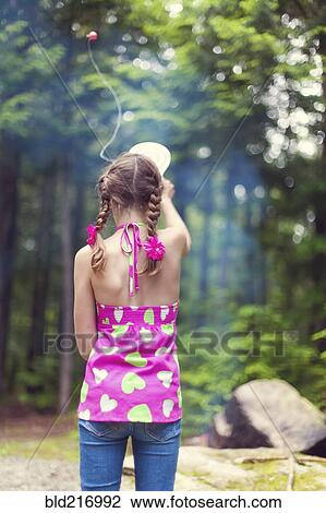 Stock Image - Caucasian girl playing with toy in forest. Fotosearch