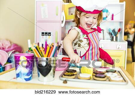 Stock Photo - Caucasian girl playing with toy kitchen. Fotosearch
