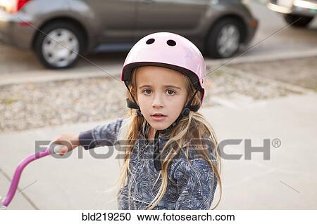 Stock Image - Caucasian girl riding bicycle on sidewalk. Fotosearch