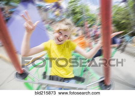 Stock Image - Caucasian girl riding roller coaster in amusement park. Fotosearch