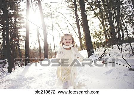 Stock Image - Caucasian girl running in snowy forest. Fotosearch