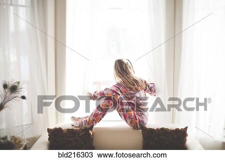Stock Image - Caucasian girl sitting in window. Fotosearch