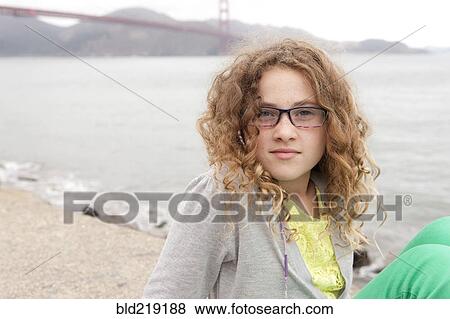 Stock Photo - Caucasian girl sitting on beach near Golden Gate Bridge, San Francisco, California, United States. Fotosearch