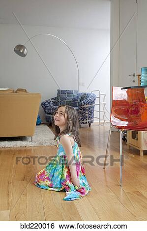 Stock Photograph - Caucasian girl sitting on living room floor. Fotosearch
