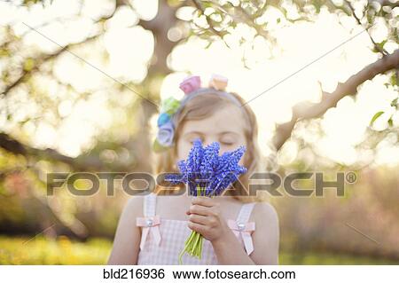 Stock Photograph - Caucasian girl smelling flowers outdoors. Fotosearch