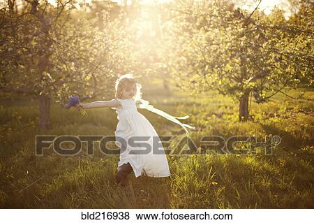 Stock Photo - Caucasian girl spinning in grass. Fotosearch