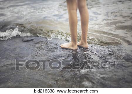 Stock Photo - Caucasian girl standing in ocean waves. Fotosearch