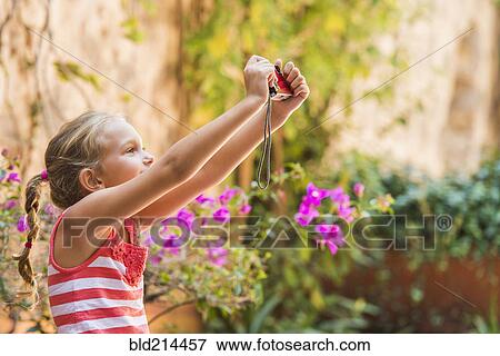Stock Photo - Caucasian girl taking photograph outdoors. Fotosearch