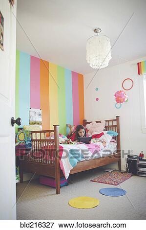Stock Photo - Caucasian girl using digital tablet in bedroom. Fotosearch