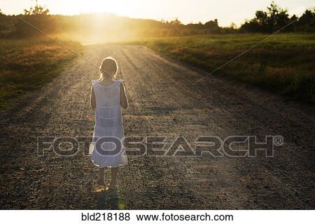 Stock Photo - Caucasian girl walking on dirt road. Fotosearch
