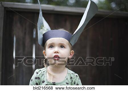 Stock Photo - Caucasian girl wearing paper hat in backyard. Fotosearch