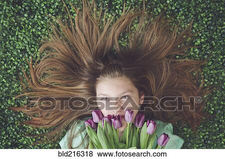 Caucasian girl with tulips laying in grass View Large Photo Image Stock Photo - Caucasian girl with tulips laying in grass. Fotosearch