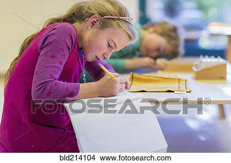 Picture - Caucasian girl writing in classroom. Fotosearch