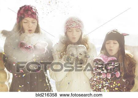 Stock Photo - Caucasian girls blowing snow off mittens. Fotosearch