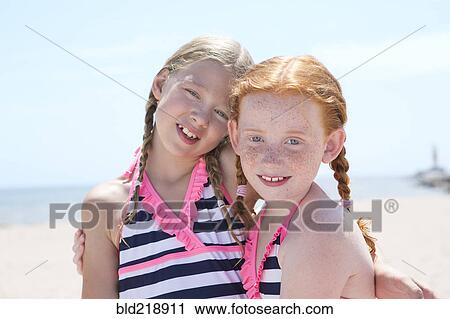 Stock Image - Caucasian girls hugging on beach. Fotosearch