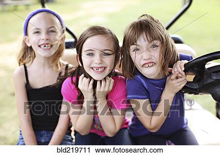 Stock Image - Caucasian girls making faces in golf cart. Fotosearch