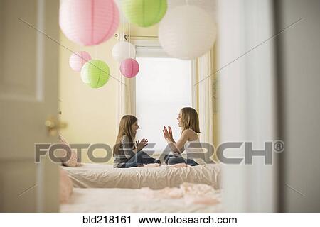 Stock Image - Caucasian girls playing clapping game in bedroom. Fotosearch