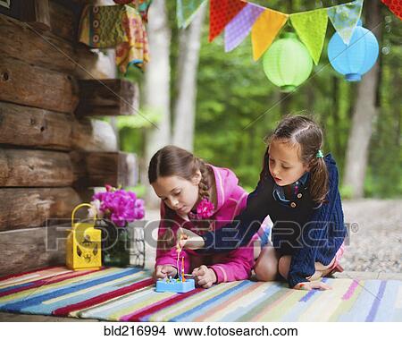 Picture - Caucasian girls playing with toy on cabin porch. Fotosearch