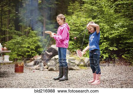 Stock Photo - Caucasian girls playing with toys in forest. Fotosearch