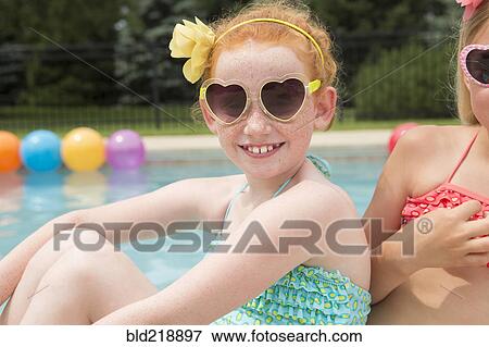 Stock Photo - Caucasian girls smiling near swimming pool. Fotosearch