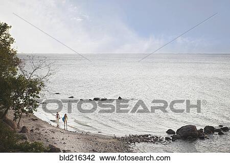 Stock Image - Caucasian girls standing on remote beach. Fotosearch