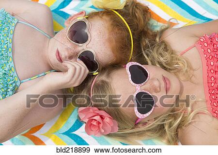 Stock Photo - Caucasian girls sunbathing in heart-shaped sunglasses. Fotosearch