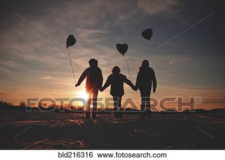 Stock Photograph - Caucasian girls walking with balloons at sunset. Fotosearch