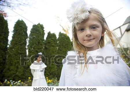 Stock Photo - Caucasian girls wearing white dresses walking in garden. Fotosearch