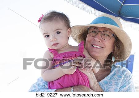 Caucasian grandmother and granddaughter sitting under umbrella View Large Photo Image Stock Photo - Caucasian grandmother and granddaughter sitting under umbrella. Fotosearch