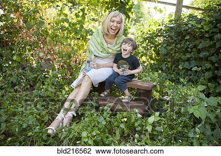 Stock Image - Caucasian grandmother and grandson sitting in garden. Fotosearch