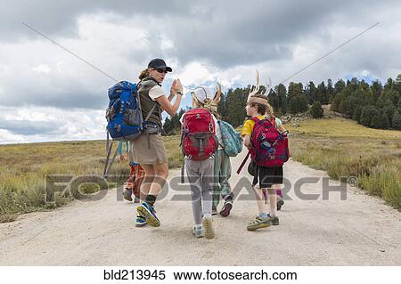 Stock Photography - Caucasian hiker leading children on path in remote landscape. Fotosearch