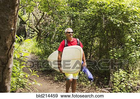 Caucasian man carrying surfboard in jungle View Large Photo Image Stock Photo - Caucasian man carrying surfboard in jungle. Fotosearch