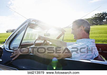 Stock Photo - Caucasian man driving classic convertible. Fotosearch