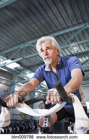Caucasian man exercising on stationary bicycle View Large Photo Image Stock Photo - Caucasian man exercising on stationary bicycle. Fotosearch