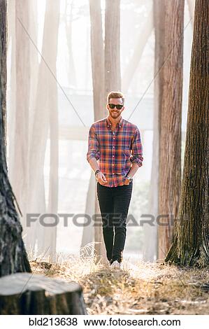 Stock Photo - Caucasian man exploring sunny forest. Fotosearch