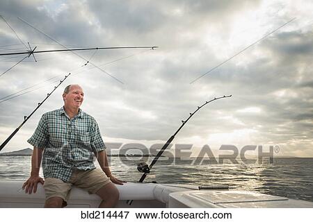 Stock Photo - Caucasian man fishing from boat in ocean. Fotosearch